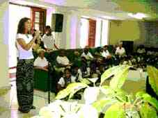Patricia Rodr�guez, de la Oficina del Historiador, habla en la inauguraci�n. A su izquierda, ancianos residentes disfrutan en la amplia Sala Polivalente de la Residencia Protegida de la ceremonia junto a ni�os escolares del �rea, que se les unieron en j�bilo